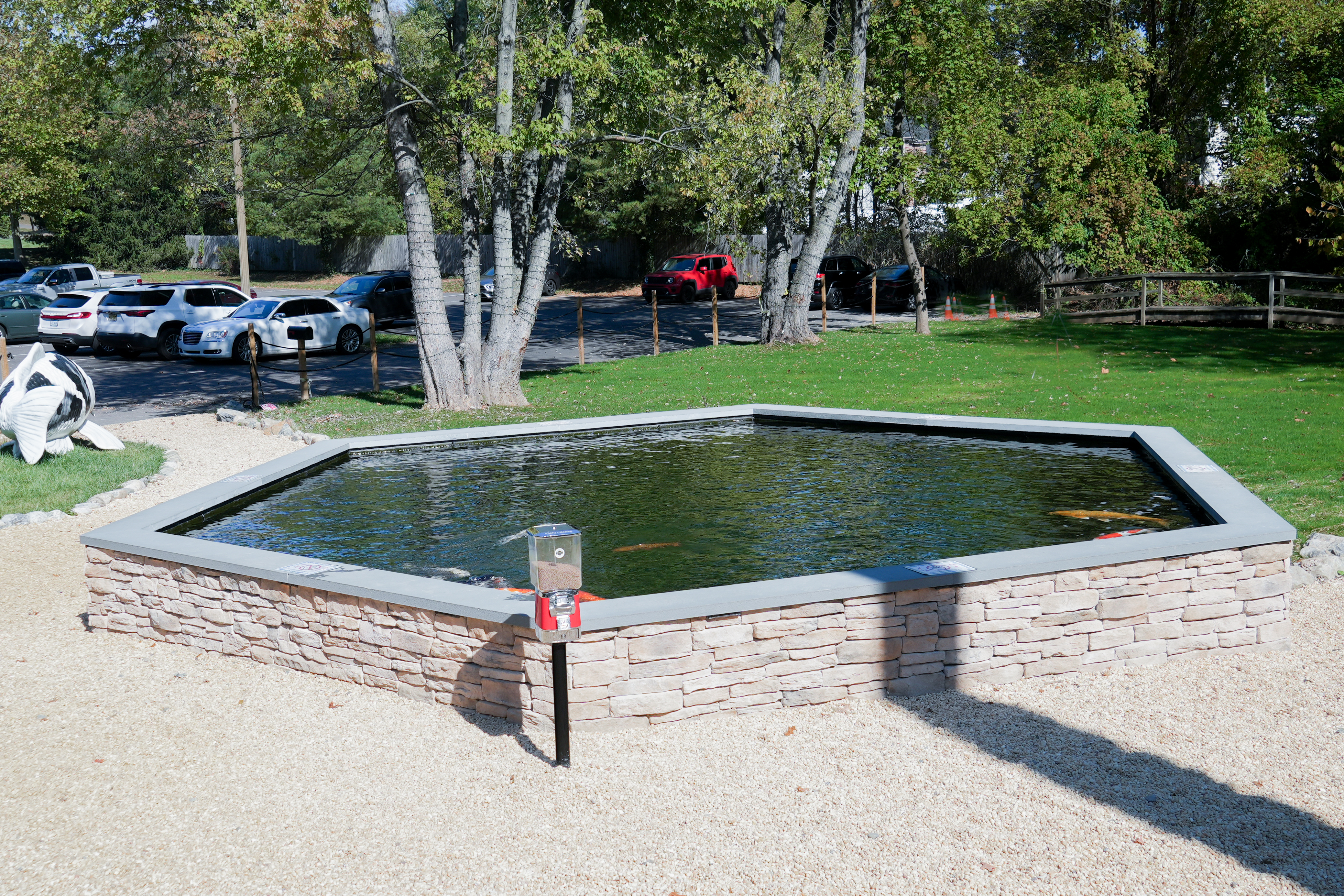 Constructed from durable fiberglass, the pond’s sides were meticulously finished with a colored gel coat for a sleek, polished appearance. A manufactured veneer surrounds the structure, complementing the patio design while offering durability and aesthetic appeal.